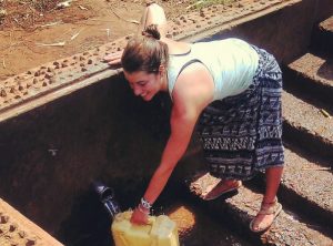 Volunteer in Africa fetching water a natural spring well