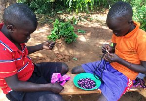 ugandan children making beaded crafts