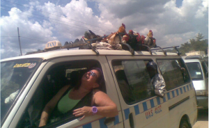 A volunteer travelling by public transport in Uganda. The taxi has chickens tied to the roof!