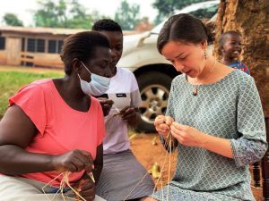 volunteer learning basket weaving in Uganda